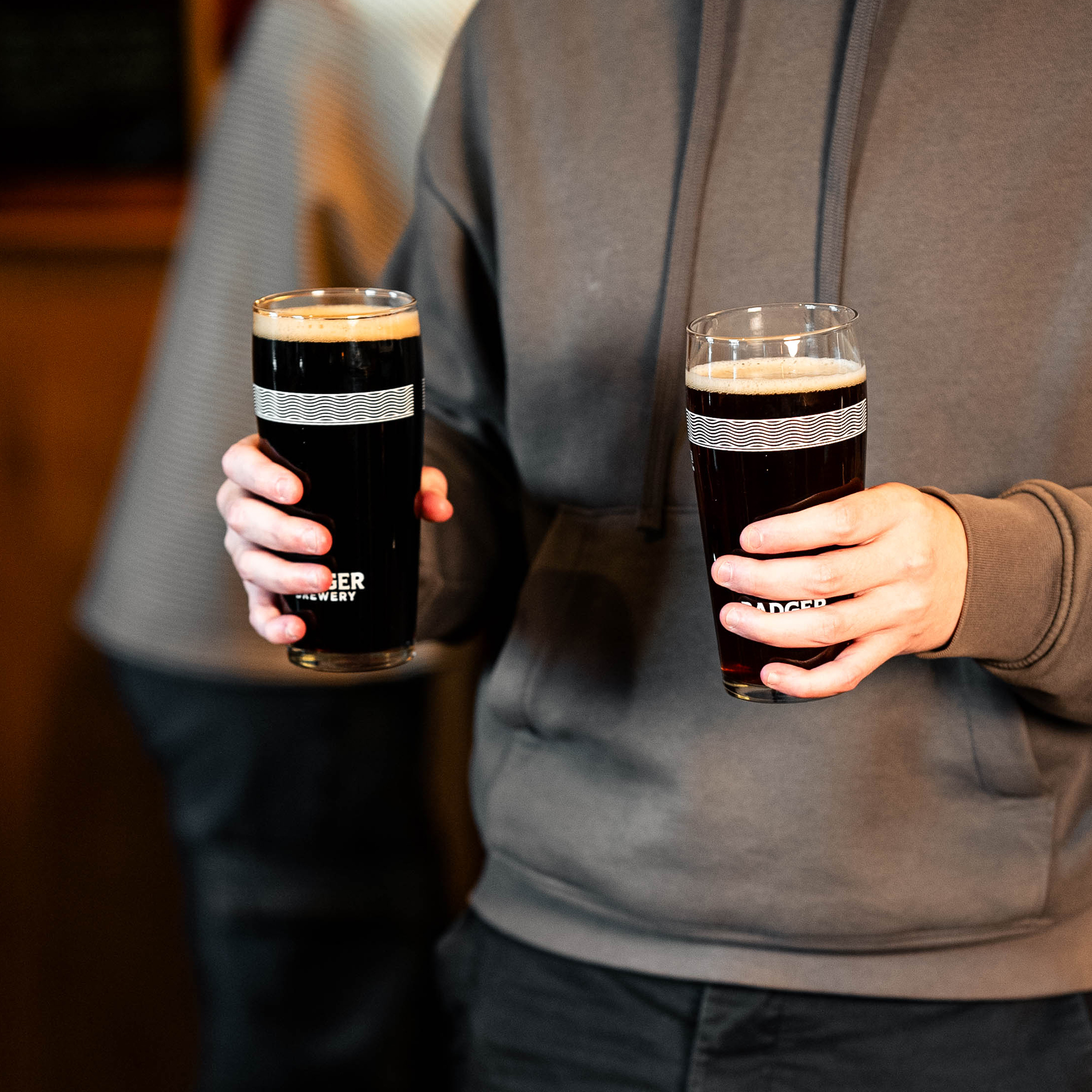 Person carrying two Badger Pint Glasses